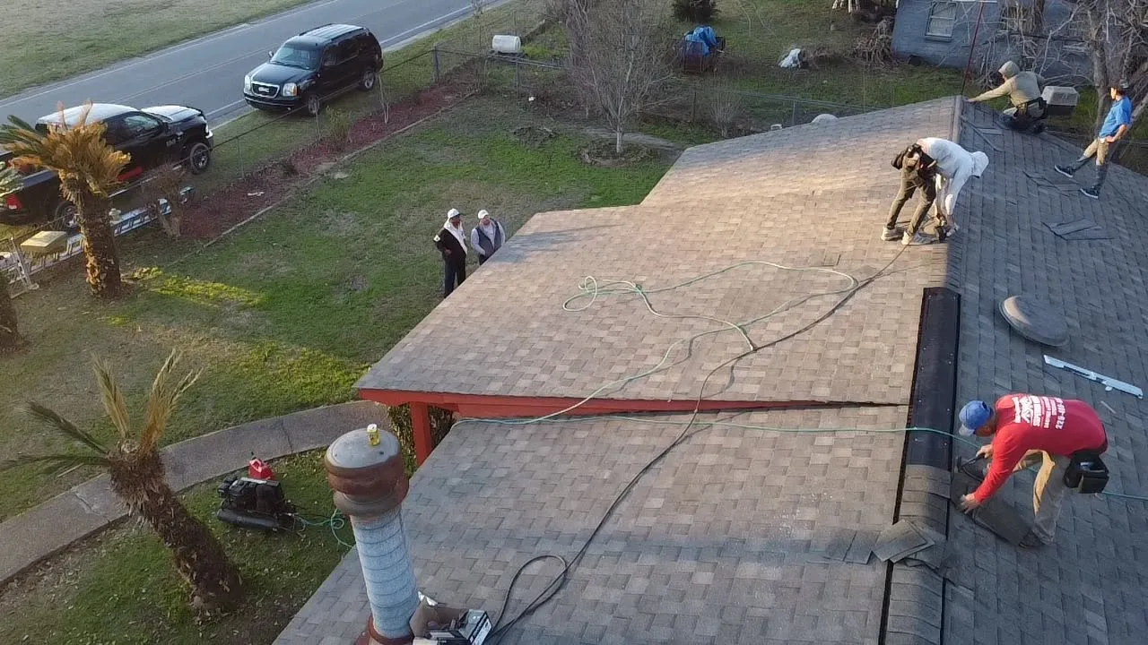 Roofing crew tearing off an old shingle roof on a single-story home