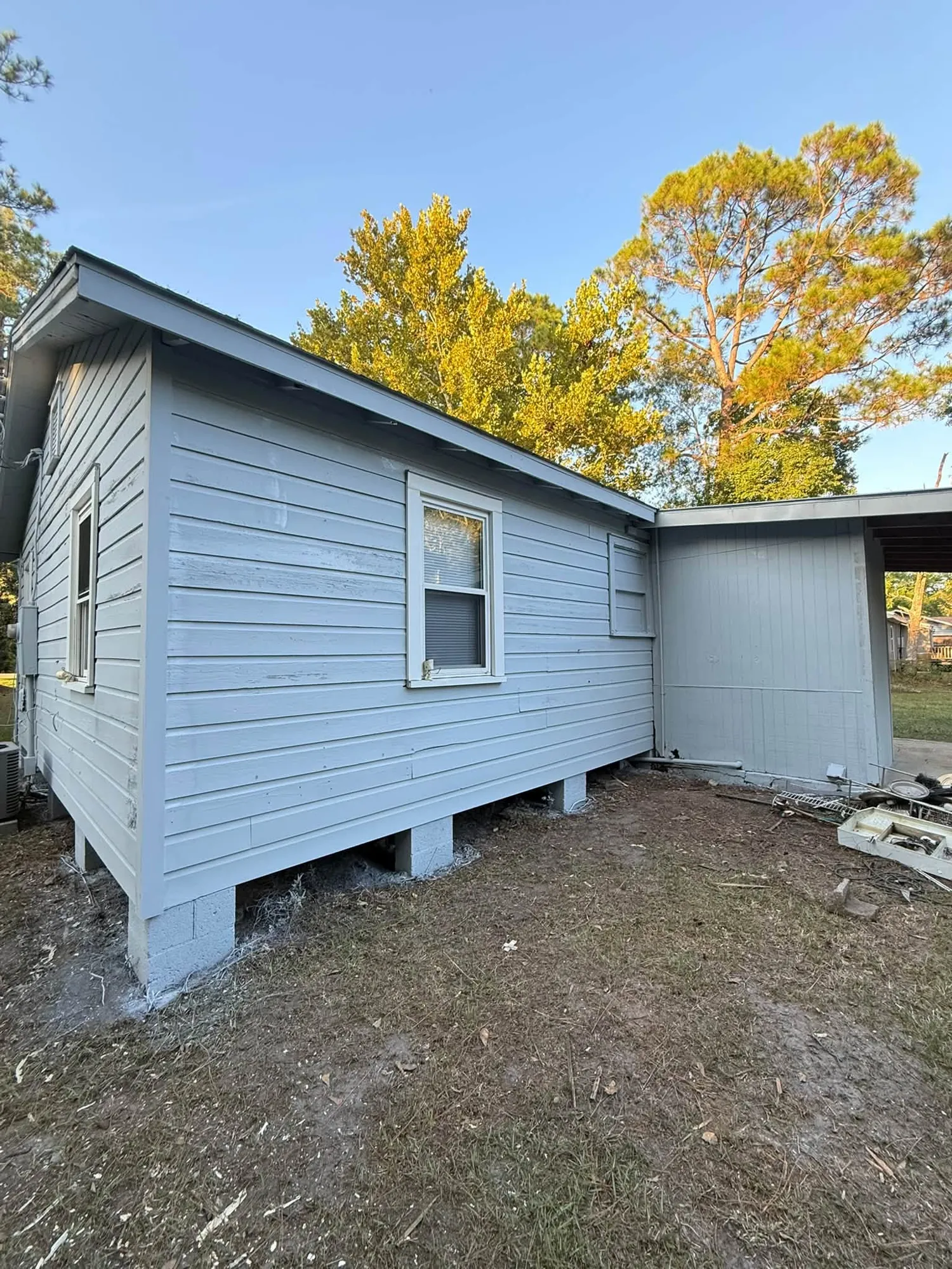 Rear of a raised home finished in gray vinyl siding