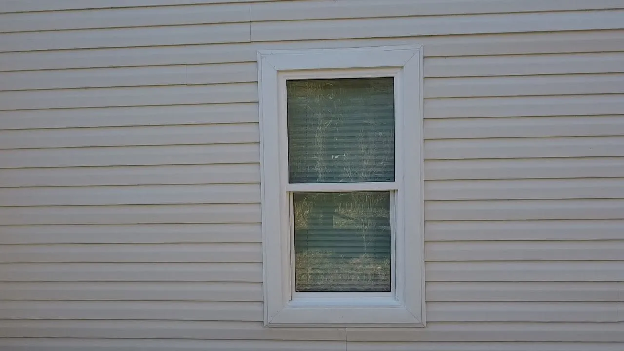 Window framed in new light vinyl siding