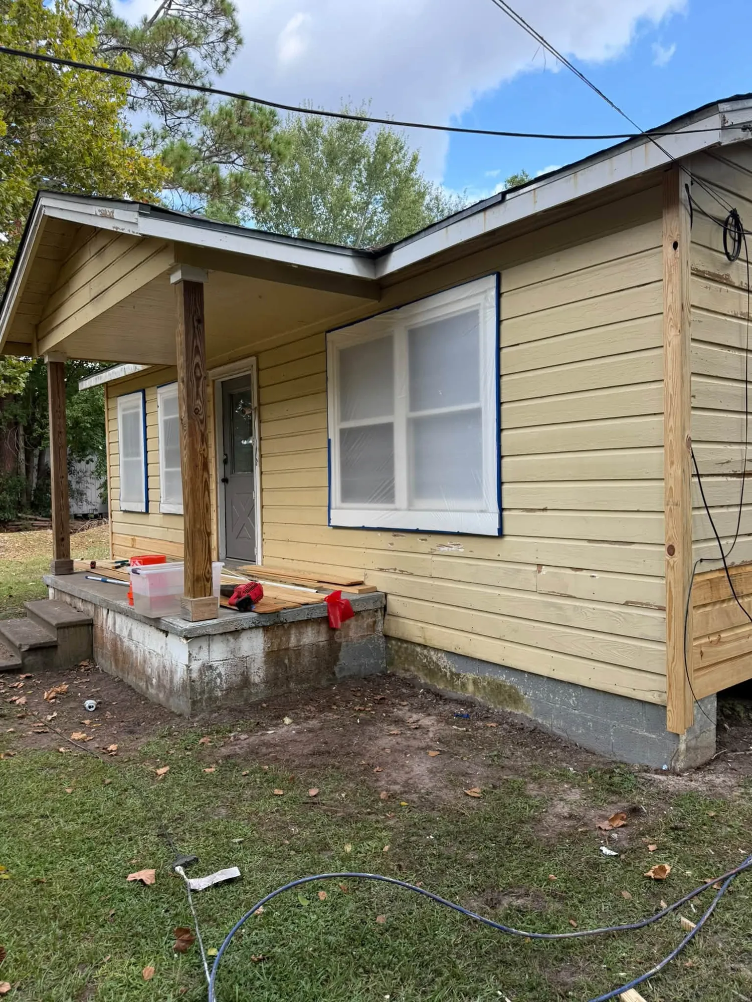 Yellow lap siding beside a front porch during repairs