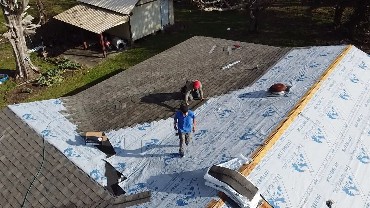 Crew rolling out synthetic underlayment over roof decking
